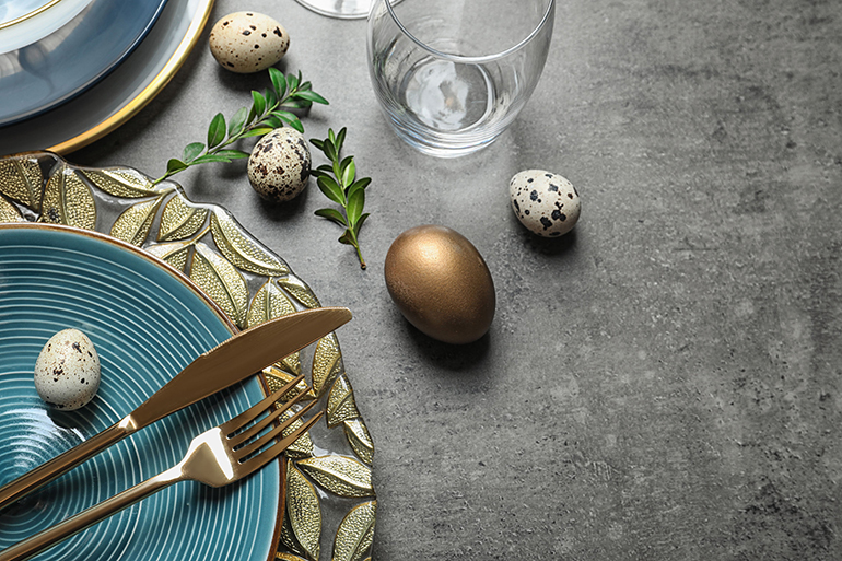 Festive Easter table setting with eggs on color background, above view. Space for text