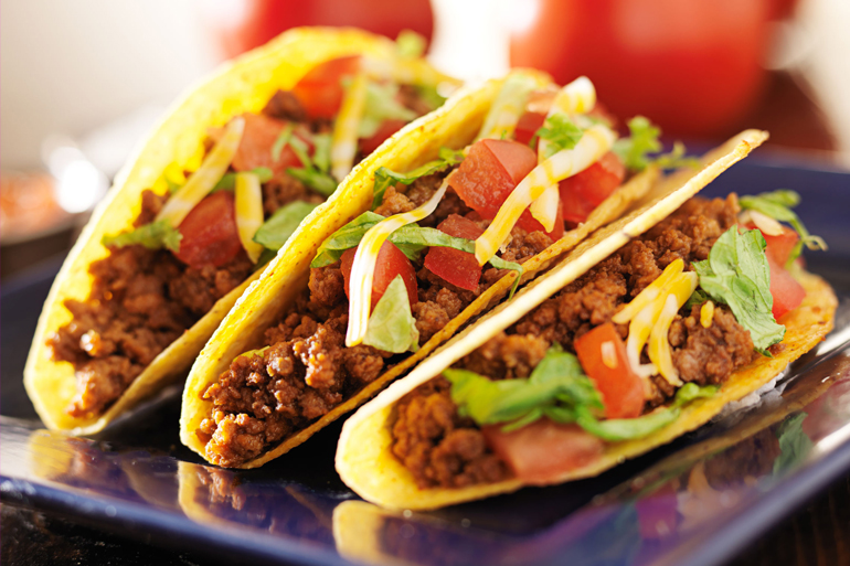 three beef tacos with cheese, lettuce and tomatos