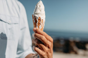 Close up of hand of man holding a melting ice cream cone. Man holding an ice cream on sunny day.