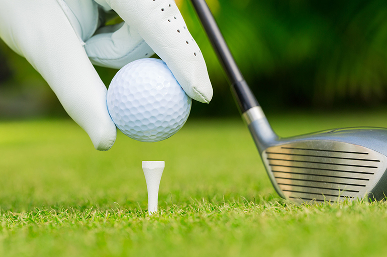 Close up view of golf ball on tee on golf course