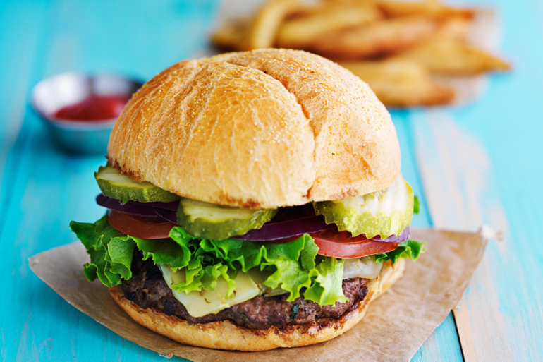 cheeseburger with fries and ketchup on rustic table top