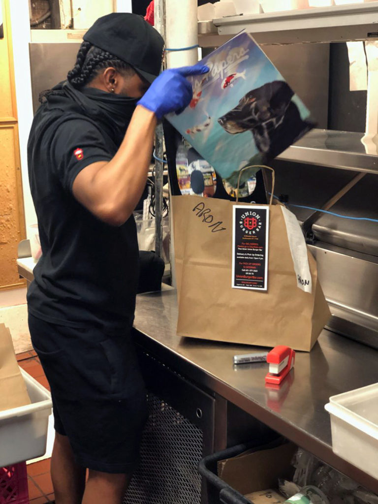 Union Burger Bar prepares takeout order with an issue of Dan's Papers