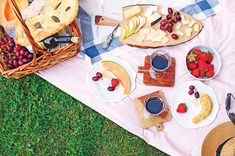 Summer picnic with cheese, wine, fruits and bread. Picnic at the park, flat lay, copy space.