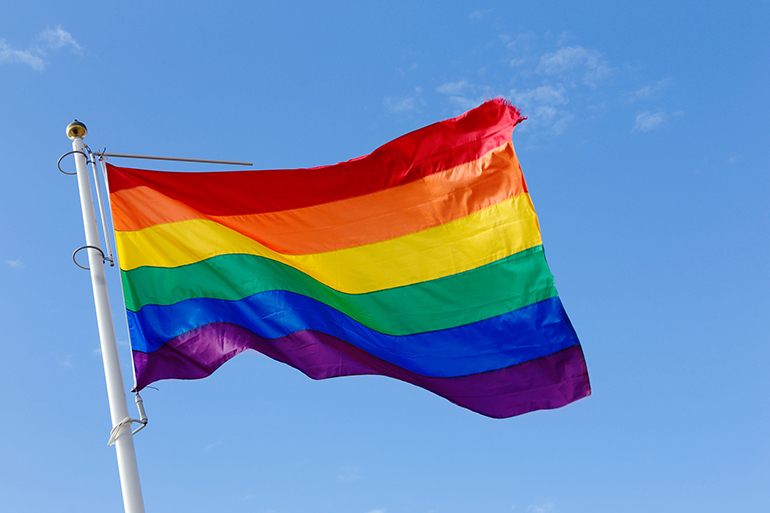 Close-up of a rainbow flag on blue sky.