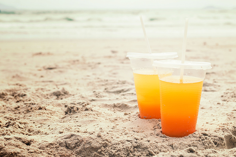 Orange juice in a glass on the beach. Summer concept.
