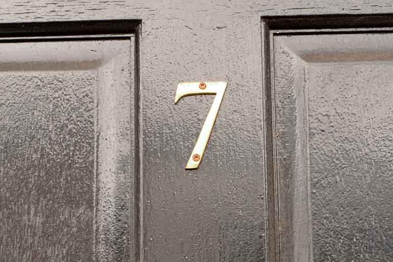 House number 7 sign on black door with brass door knocker