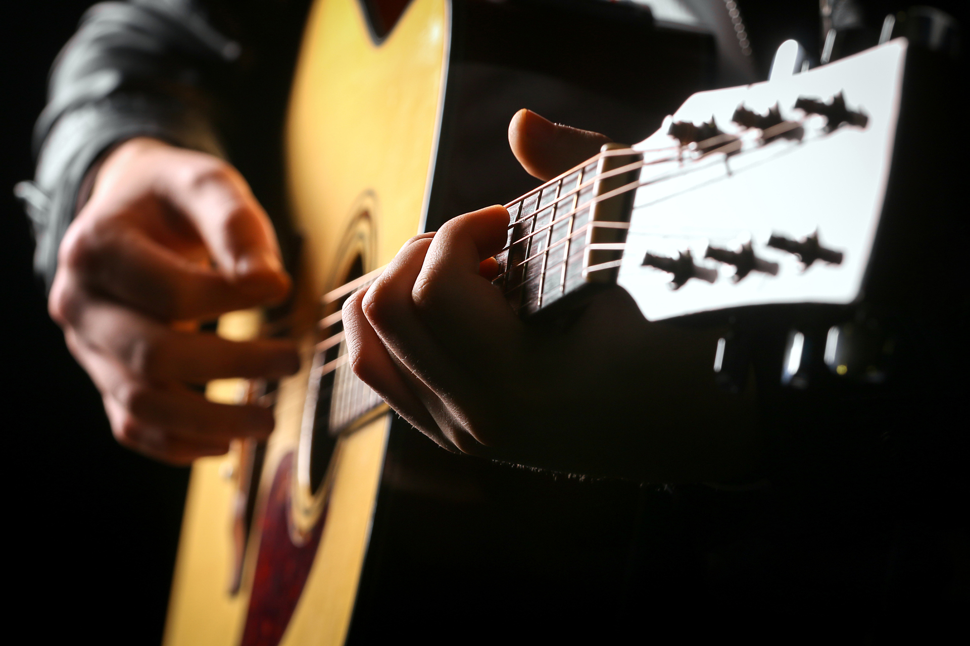 Young men playing the guitar with black background