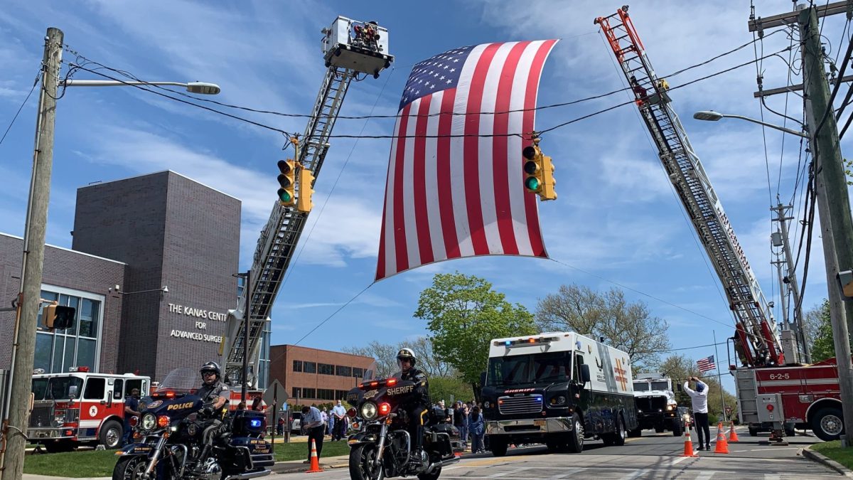 The flag flew over Roanoke Avenue in Riverhead while police and sheriffs officers drove by Peconic Medical Center.