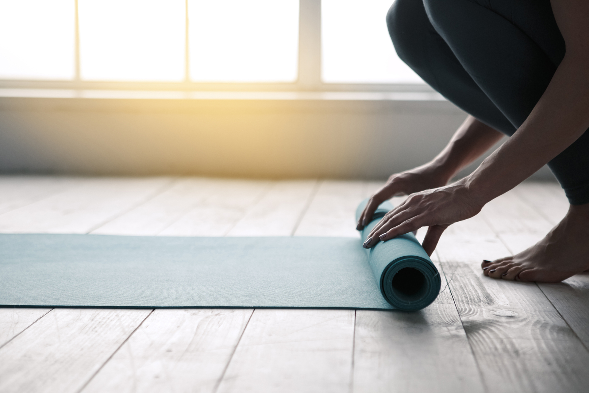 Young woman doing yoga twisting mat indoors near window