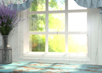 A wooden table top with a blue color and vase of lavender in front of blurred background.