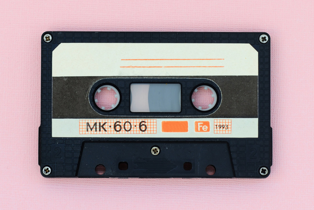 Old audio tape cassette on a pink background. Top view, old technology concept