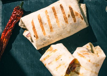 Traditional Mexican vegetarian burrito on a serving board close-up, top view