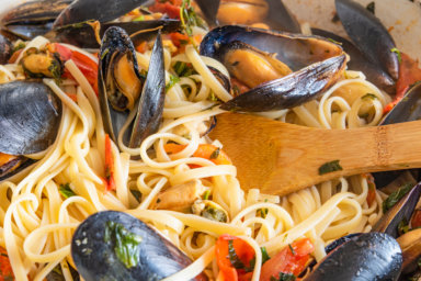 Homemade pasta with mussels in a large frying pan. Linguine with shellfish and vegetable sauce