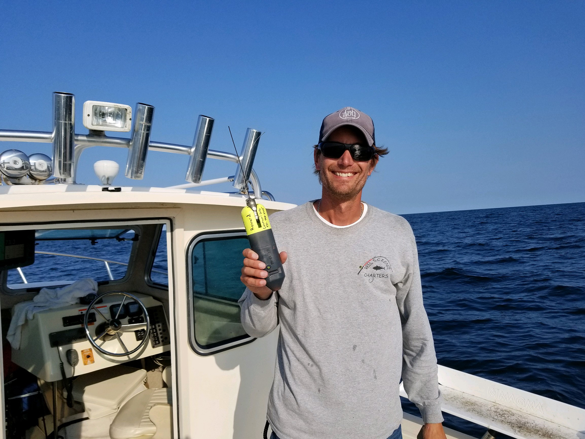 Southampton High School marine biology teacher Greg Metzger proudly displays a CATS-cam tag placed on the first thresher shark he caught after it was retrieved.