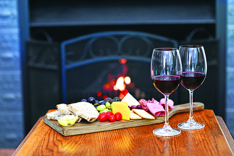 Dessert wine and cheeseboard at fireplace selective focus