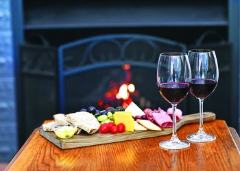 Dessert wine and cheeseboard at fireplace selective focus
