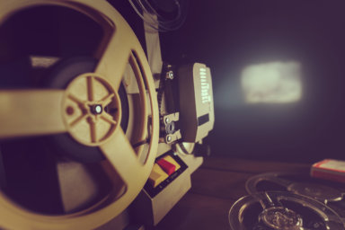 retro 8mm film projector playing old movie on the wall in dark room