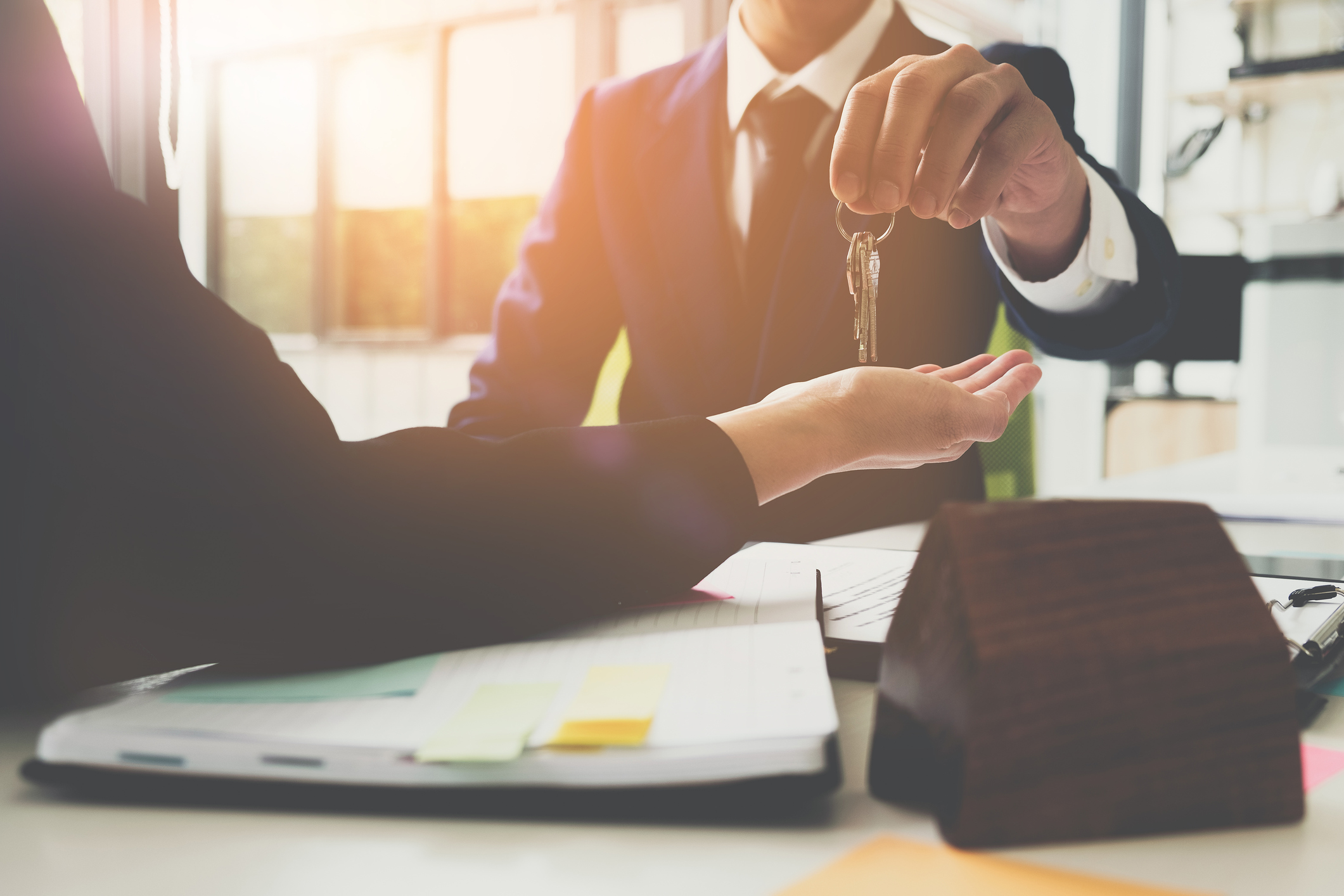 estate agent giving house keys to man and sign agreement in office