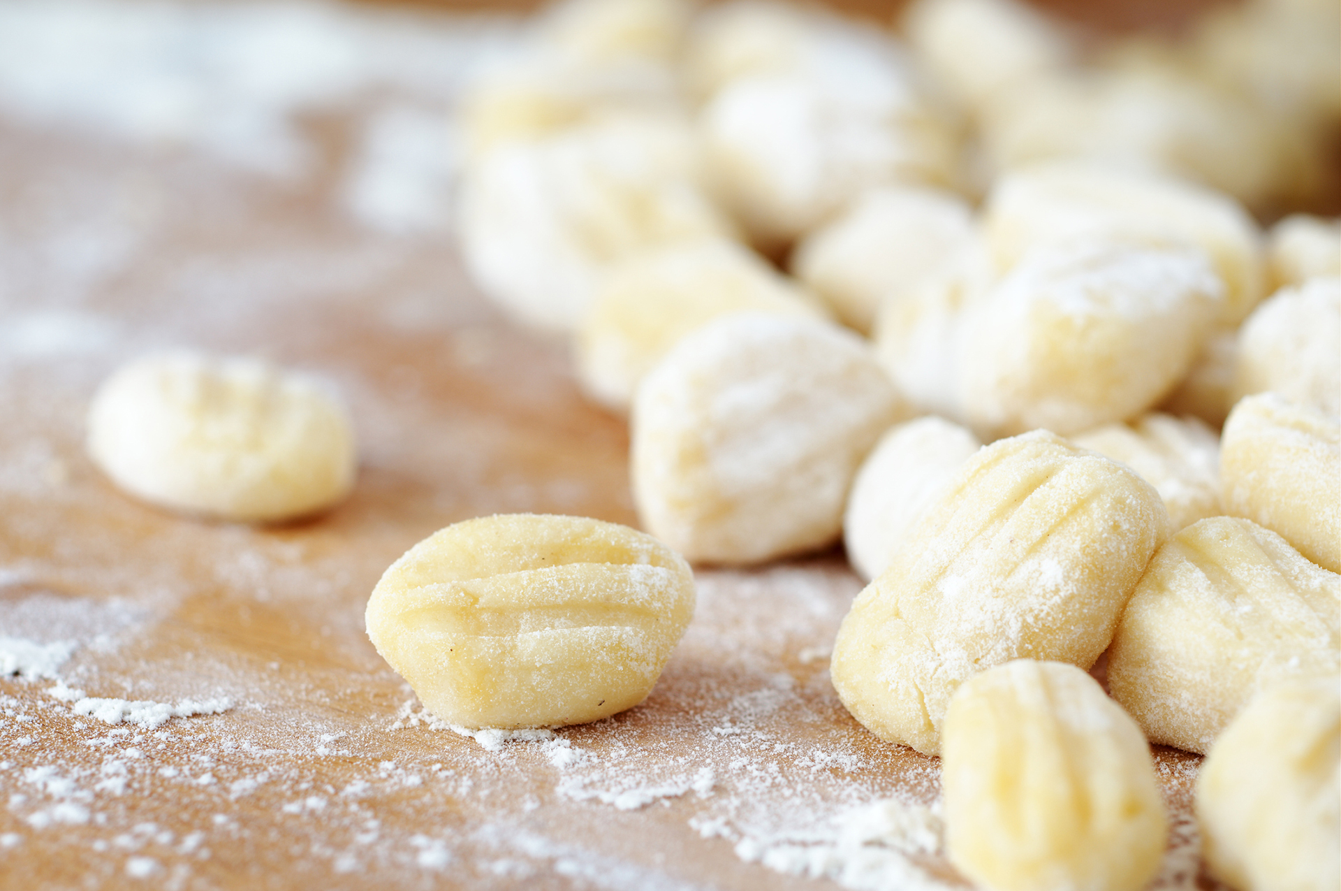 Homemade gnocchi on a flour-covered, wood surface