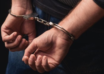 Young criminal standing in handcuffs