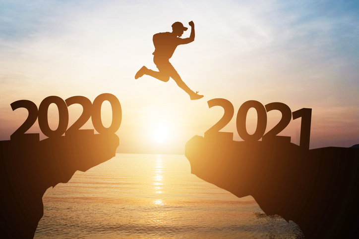 Silhouette man jump from 2020 to 2021 on cliff with sunlight for change and welcome the new year.