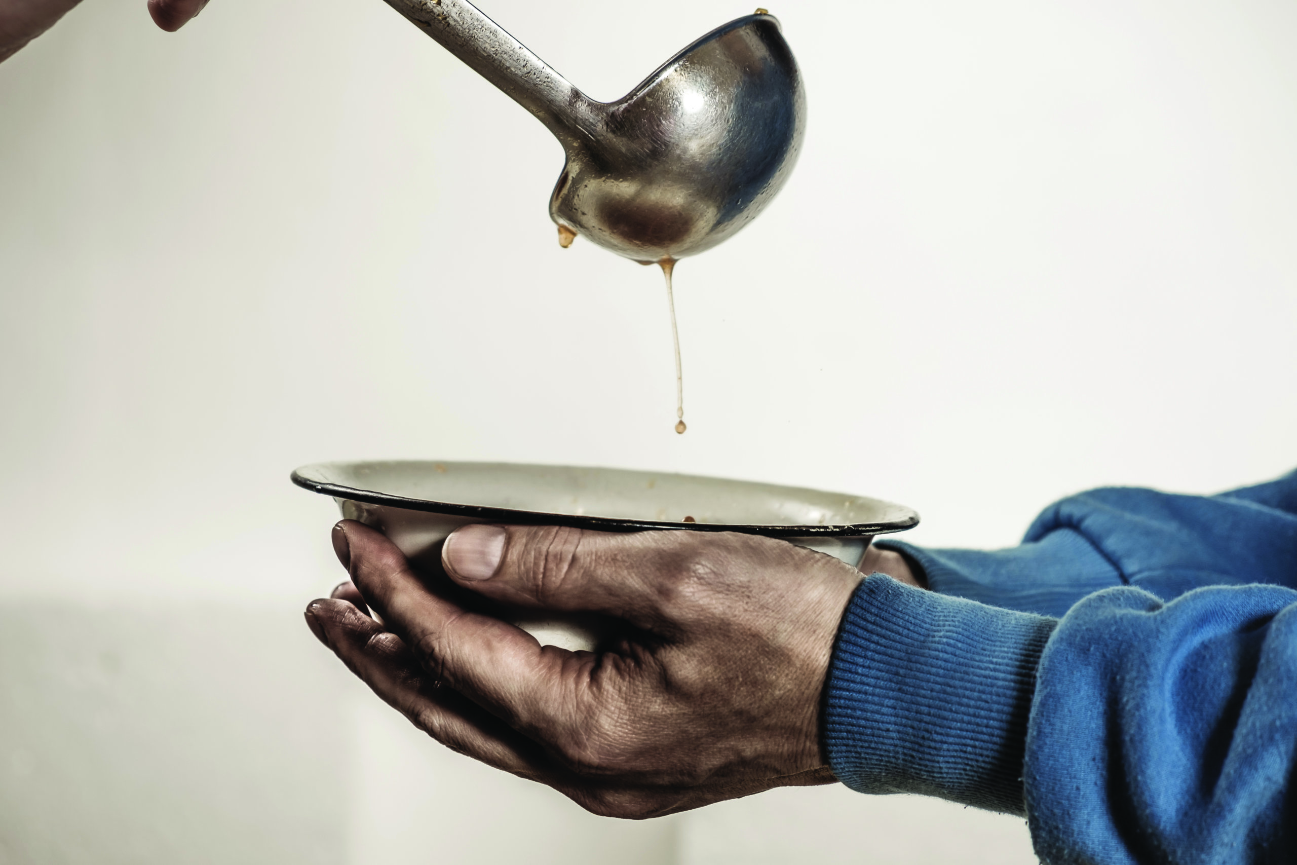 Volunteers feed the homeless. Free soup in a bowl of beggar and ladle.