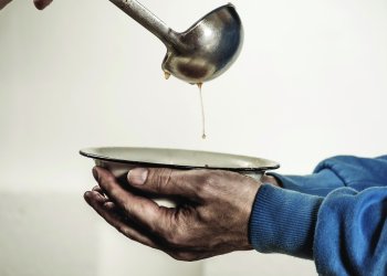 Volunteers feed the homeless. Free soup in a bowl of beggar and ladle.