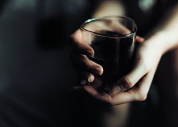 woman holds glass with whiskey. alcohol cocktail in glass. woman’s alcoholism, alcohol addict concept