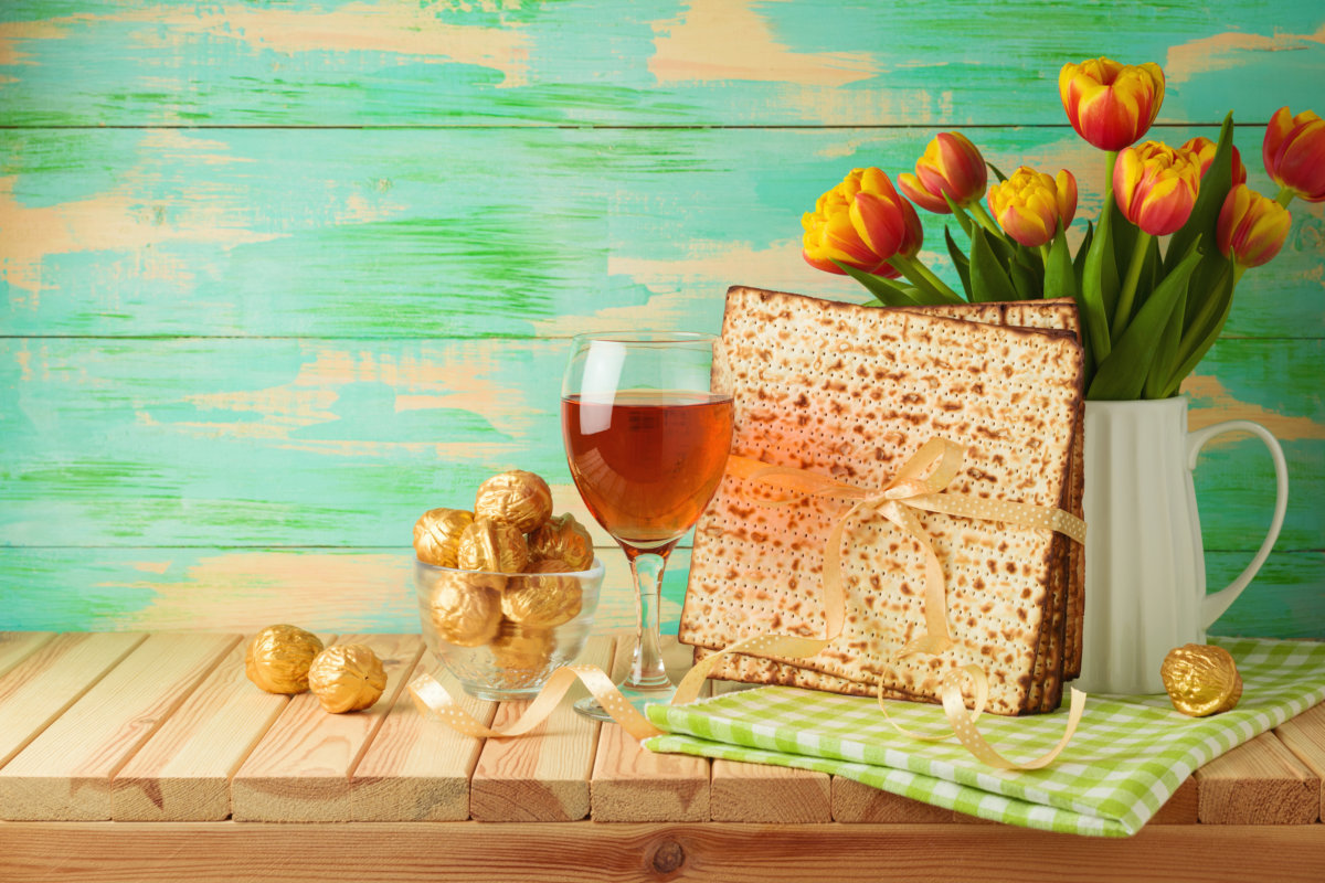 Jewish holiday Passover celebration with matzah, wine glass and tulip flowers on wooden table