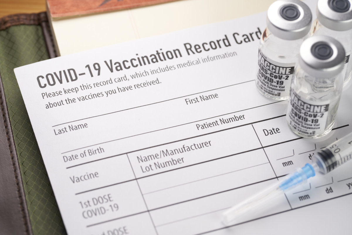 COVID-19 vaccination record card with vials and syringe