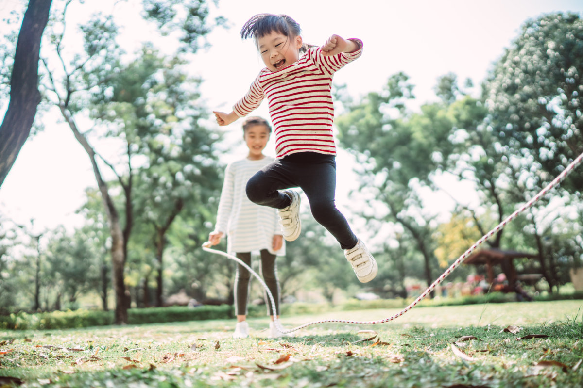 Young family jumping rope joyfully on the lawn