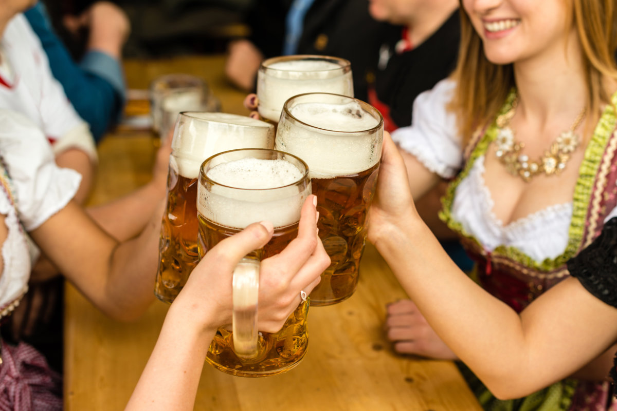 Bavarian girls in traditional Dirndl dresses are drinking beer and having fun at the Oktoberfest