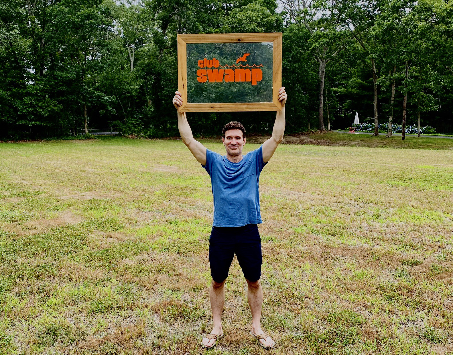 Hamptons Pride President Tom House displaying a sign for The Swamp