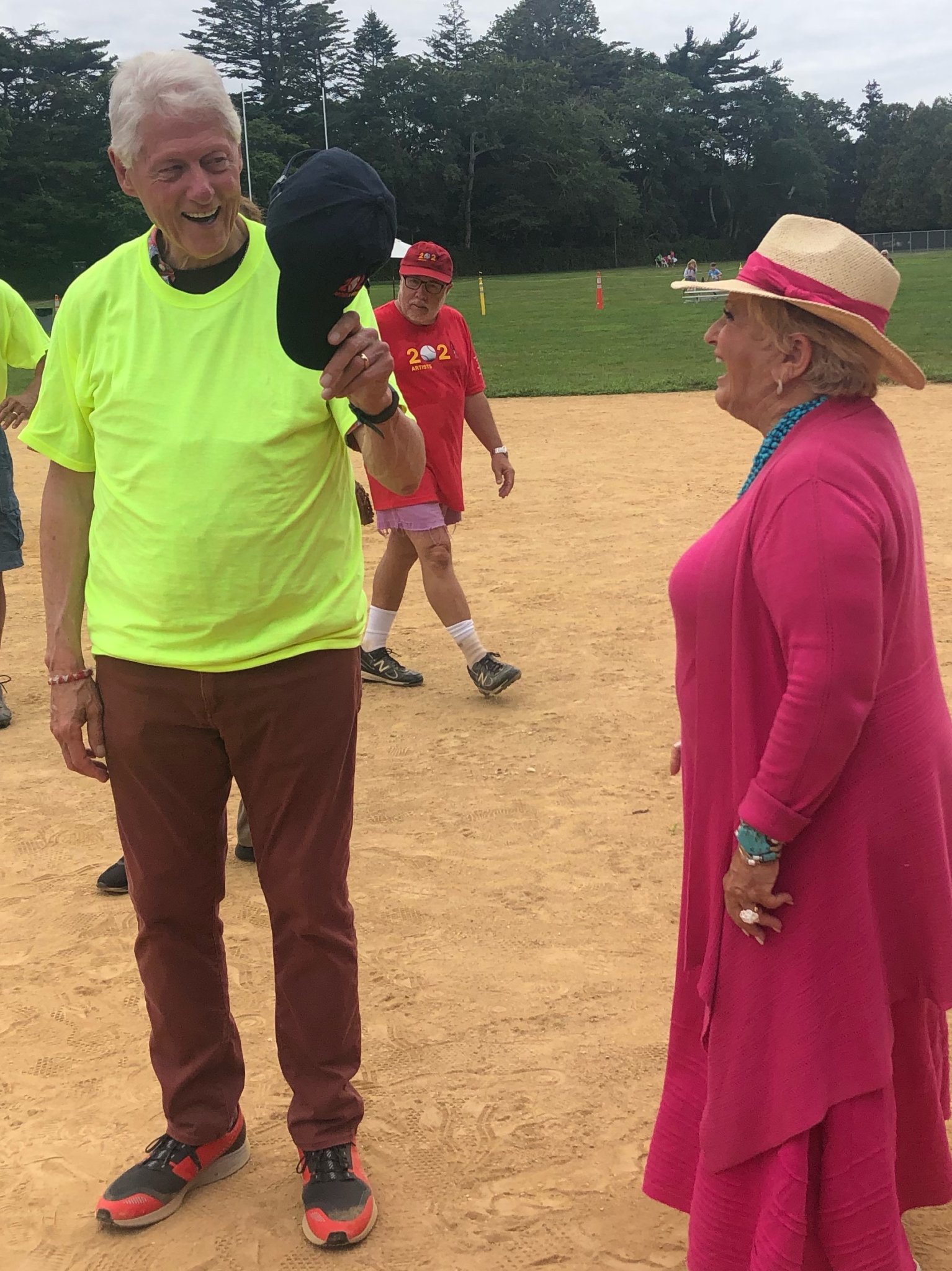 Victoria Schneps and President Bill Clinton on the Artists & Writers Game 2021 field in his neon umpire shirt