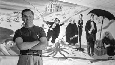Charles Addams posing with a mural he painted that once hung in a Hamptons hotel