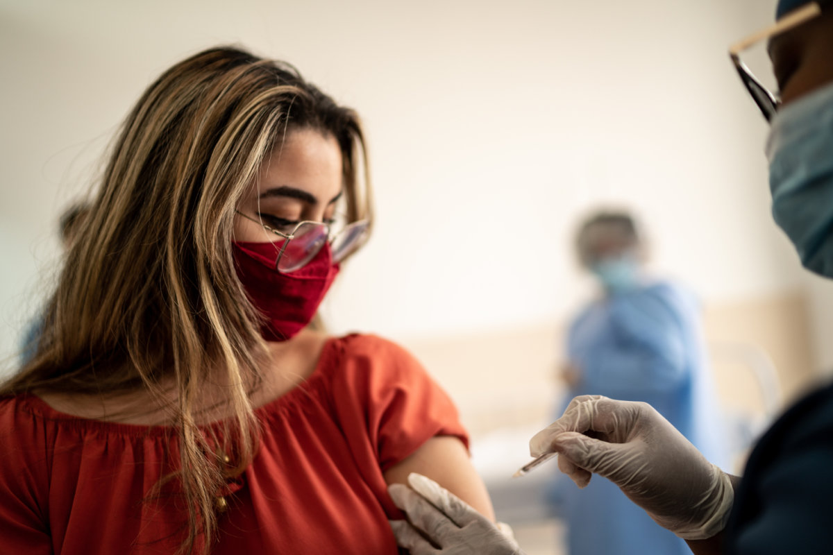Teenage Latina girl being vaccinated - wearing face mask