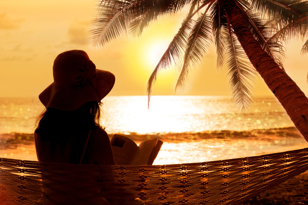 Woman reading in hammock at stunning sunset during vacation in phuket or is it Florida