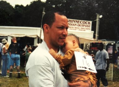 A young Asia Cofield held by her father, Jason Hansana-Cofield, at the 2001 Shinnecock Powwow