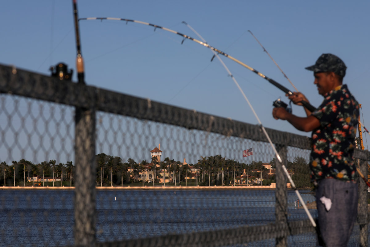U.S. President Donald Trump's Mar-a-Lago resort is seen as a local resident fishes after local authorities restricted the activities of restaurants, bars, gyms, movie theaters and other similar businesses and asked residents to practice 'social distancing' for precaution due to coronavirus disease (COVID-19) spread, in Palm Beach, Florida U.S., March 24, 2020. REUTERS/Carlos Barria