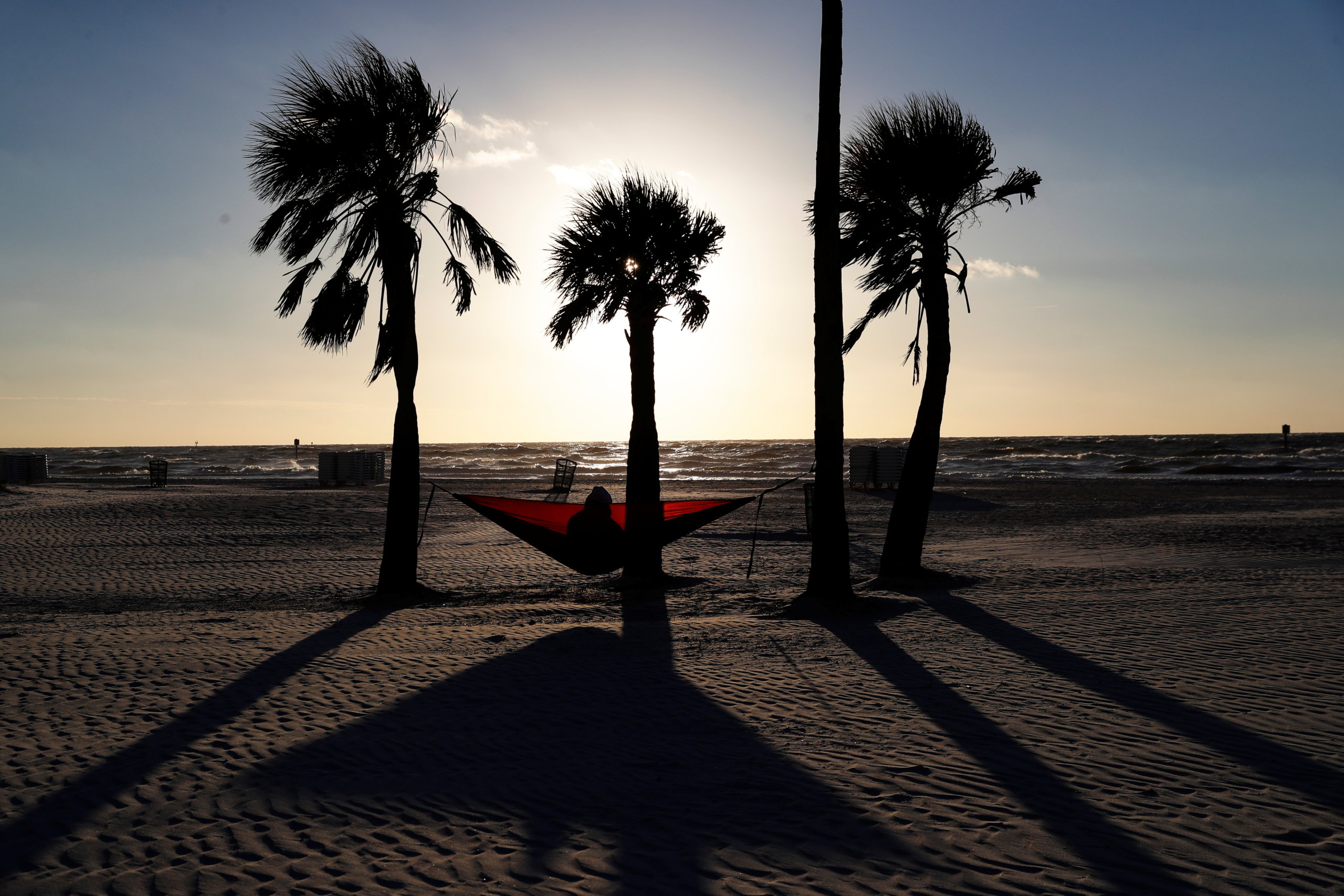 Katie Burkett sits in a hammock amid the spread of the coronavirus disease (COVID-19) beneath palm trees at sunset in Clearwater Beach, Florida, February 2, 2021. REUTERS/Shannon Stapleton