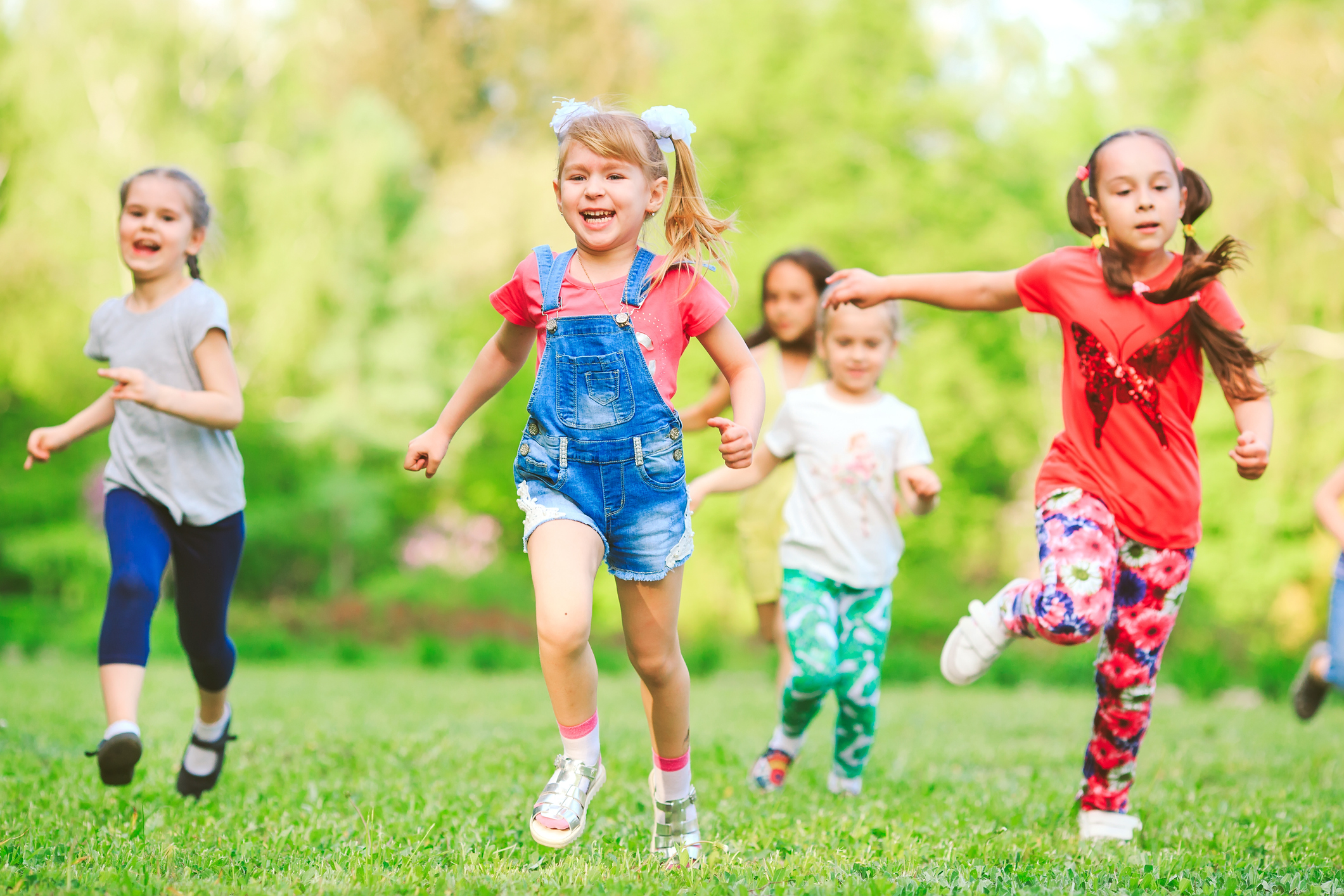 Many different kids, boys and girls running in the park on sunny summer day in casual clothes.