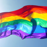 Big rainbow flag is waving in the wind with sun shining throughMore of my flag images: