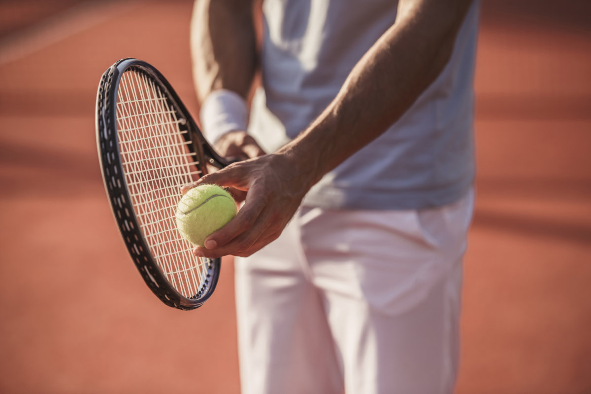 Cropped image of handsome man playing tennis on tennis court outdoors