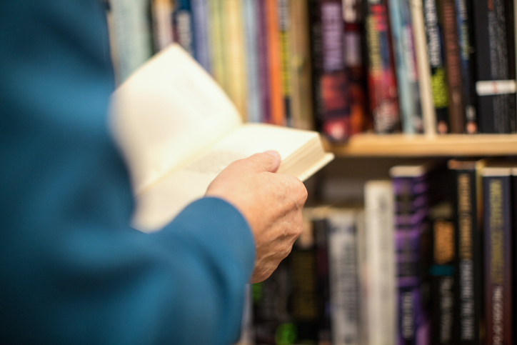 Cropped image of senior male customer holding book