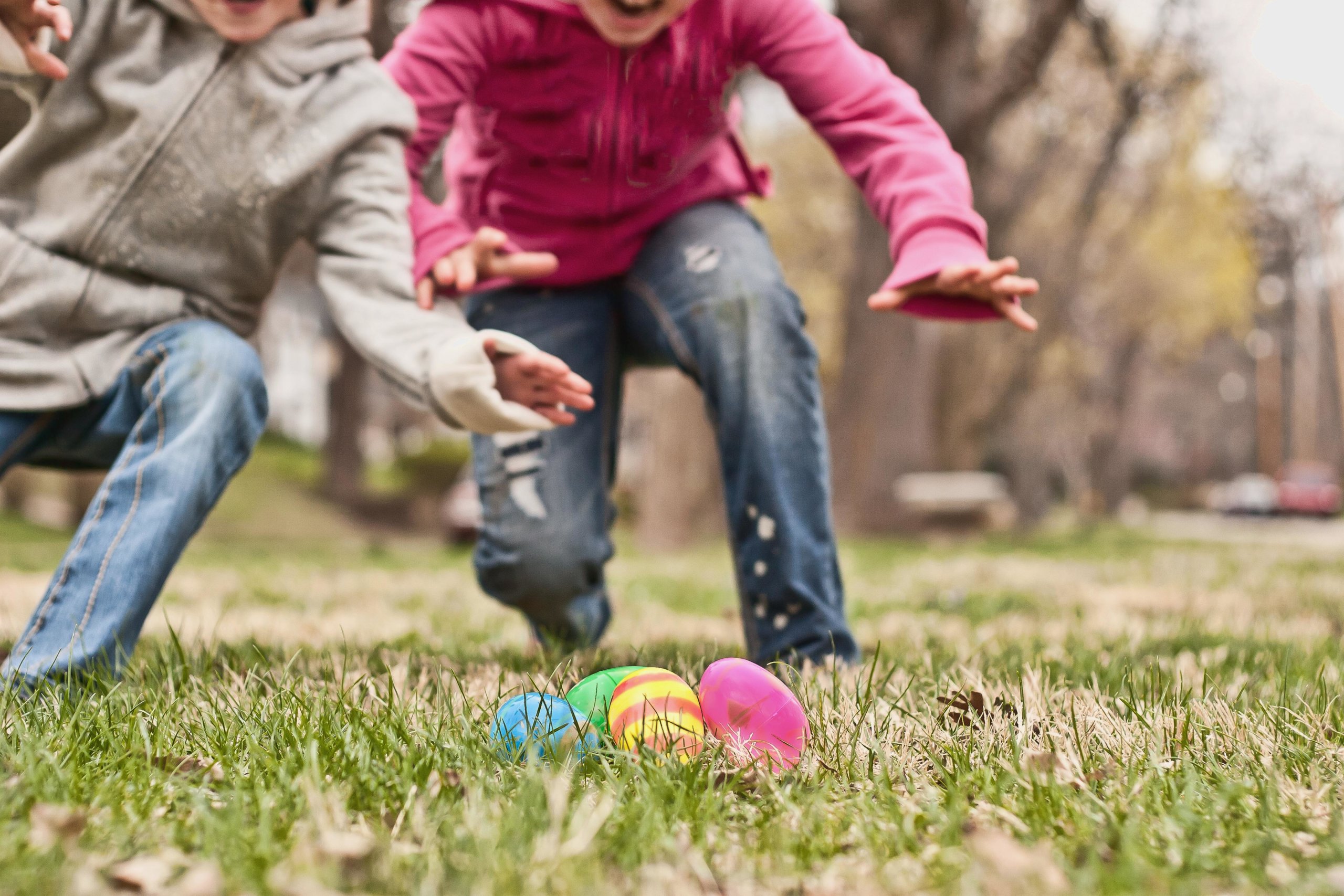 Two children running towards easter eggs during a hunt
