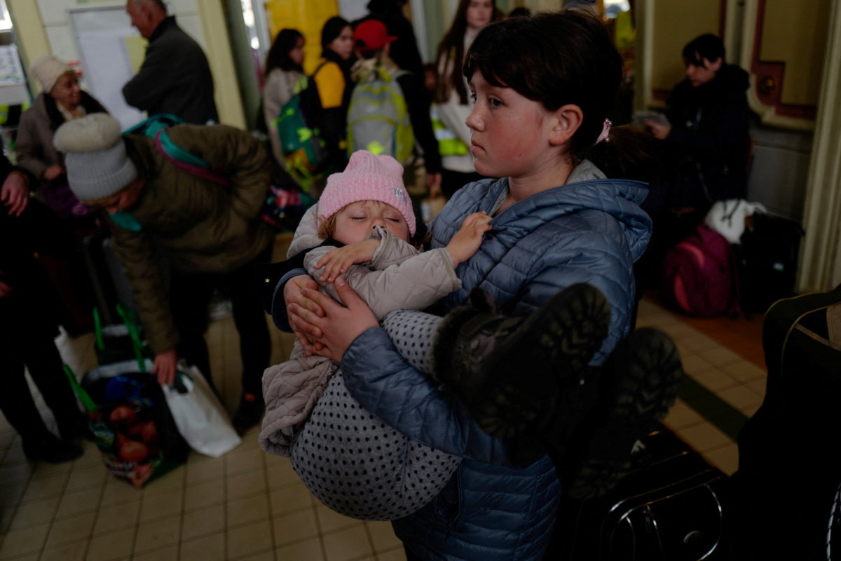 Ukrainian refugees Tania, 2, and Galina, 11, wait in the ticket hall at Przemysl Glowny train station, after fleeing the Russian invasion of Ukraine, in Poland, April 4, 2022.