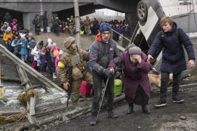 Elderly woman is assisted crossing the Irpin river while fleeing her home in Irpine, Ukraine