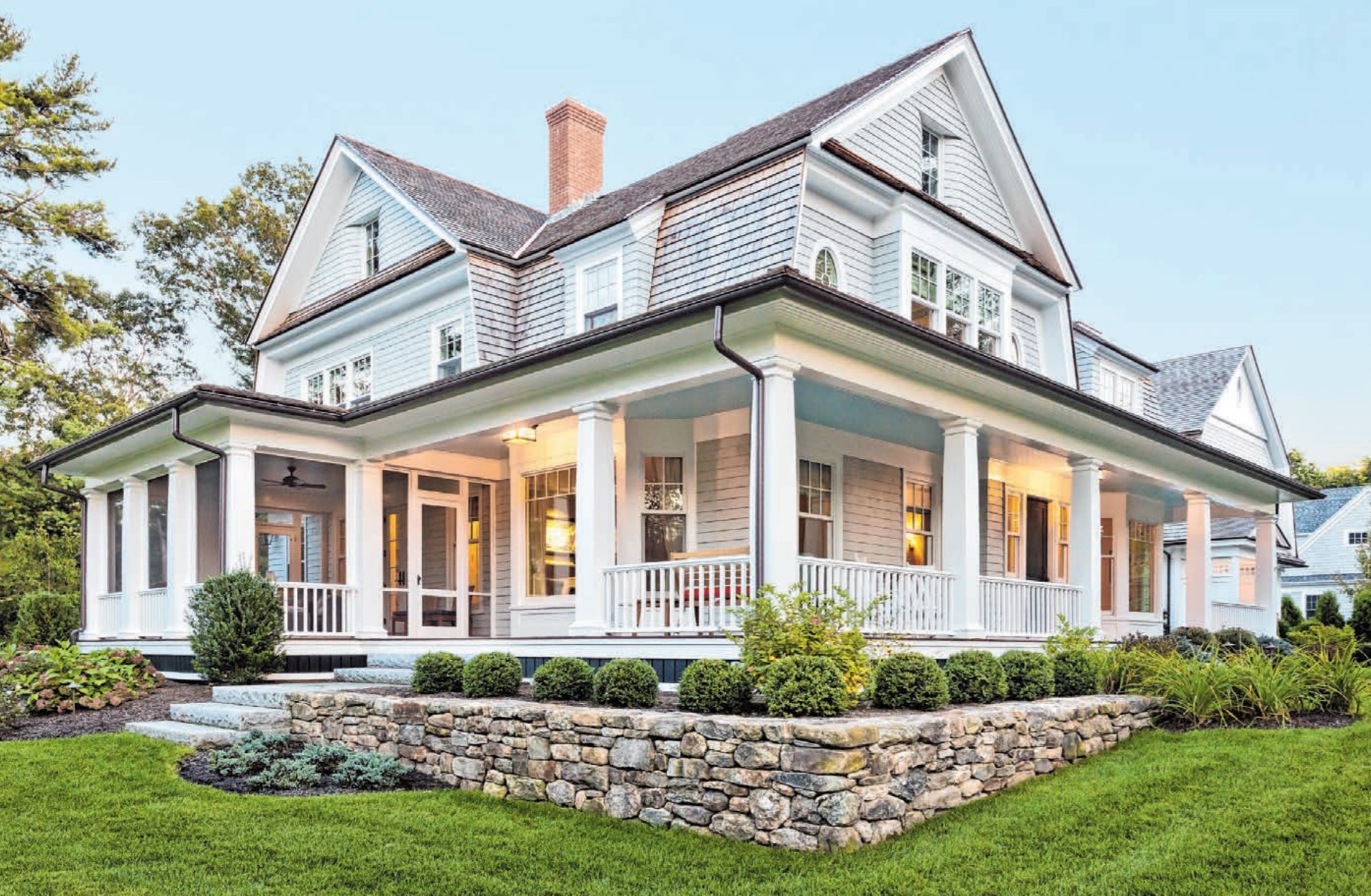 Exterior view of custom-built home with exterior lighting and manicured landscaping.