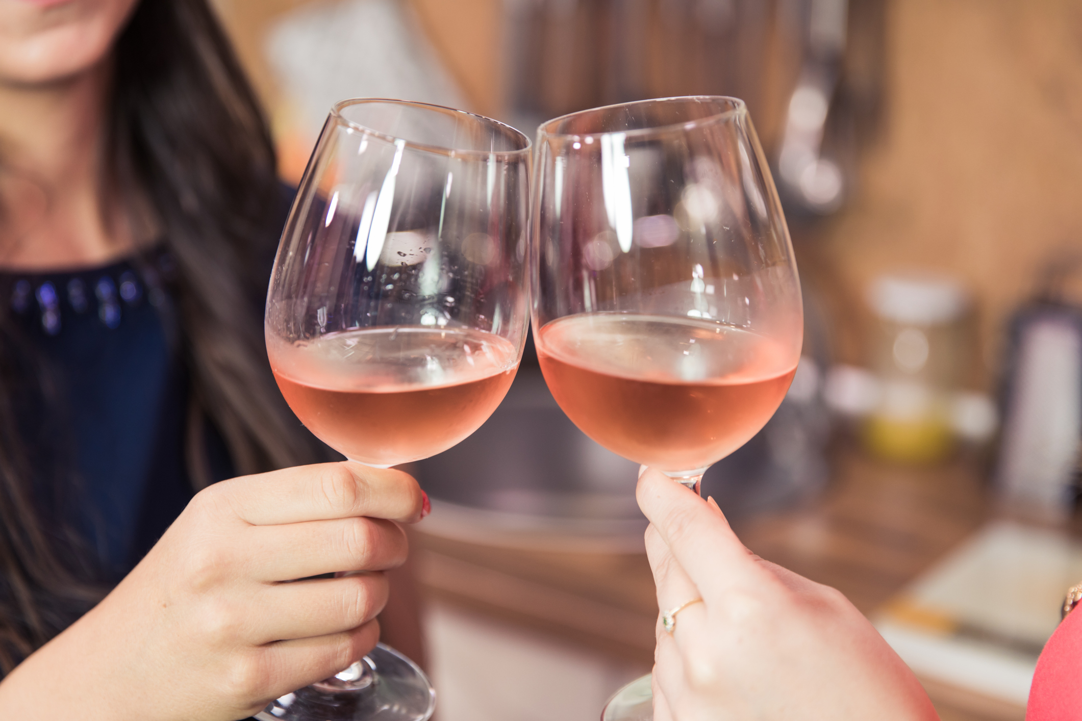 Close up of women toasting with rose wine while celebrating success.