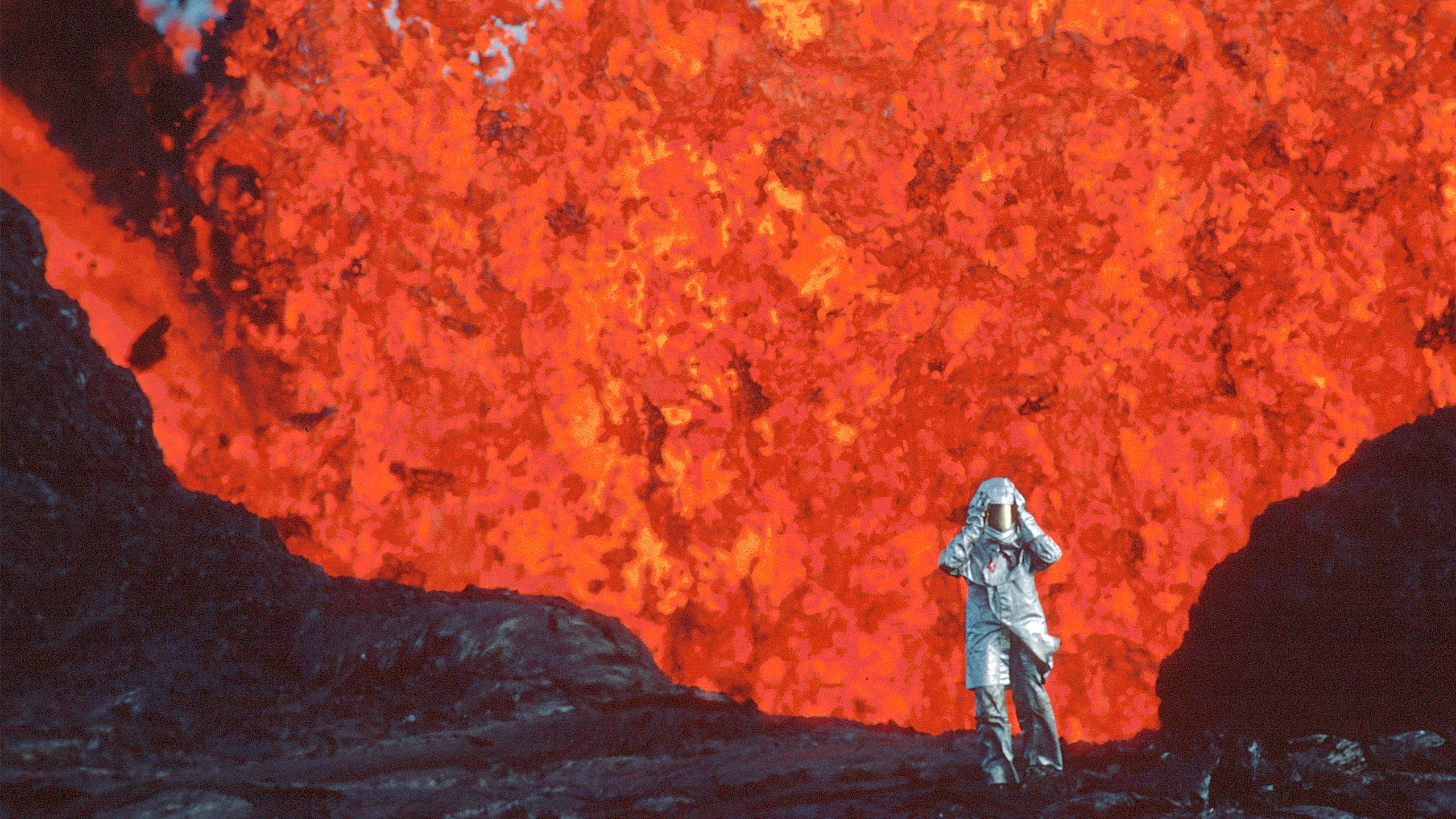 Katia Krafft wearing aluminized suit standing near lava burst at Krafla Volcano, Iceland, from 